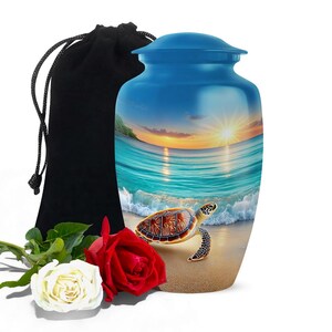 May include: A blue cremation urn with a scenic beach design featuring a sea turtle, ocean waves, and a sunset. Includes a black velvet bag and two roses, one red and one white.