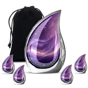 May include: A teardrop-shaped urn with a galaxy design in shades of purple and gold, with a silver decorative border. Includes a black drawstring bag and four smaller matching teardrop-shaped keepsakes.