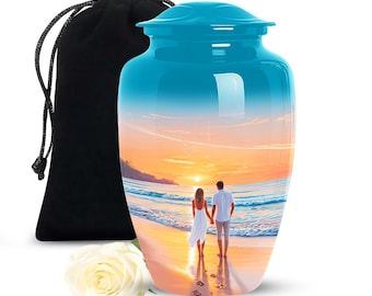 May include: A blue cremation urn with a sunset beach scene featuring a couple walking. Includes a black velvet bag and a white rose. The urn is a memorial item.