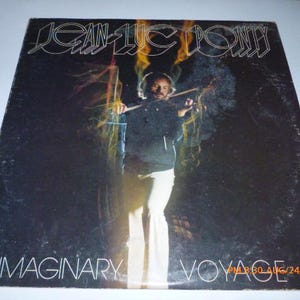 May include: Album cover for "Jean-Luc Ponty - Imaginary Voyage." The cover features a man playing a violin with a dark background and streaks of light. The artist's name is at the top, and the album title is at the bottom.