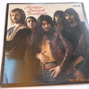 May include: Album cover for Horslips' Dancehall Sweethearts, featuring six men. The album title is in red script. The men are in various outfits, including a sequined jacket and open shirts. The RCA logo is visible.