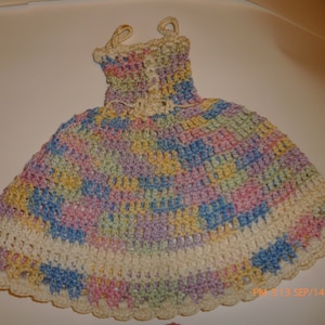 May include: A multi-colored crocheted dress with a white trim. The dress is made with a variety of pastel colors, including pink, blue, yellow, and green.
