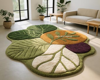 May include: A large, leaf-shaped rug with a botanical design. The rug features various shades of green, orange, white, and purple, with a textured, tufted appearance. The rug is placed on a light-colored floor in a well-lit room.