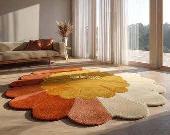May include: A large, flower-shaped rug with a vibrant color palette. The rug features petals in shades of orange, yellow, and cream. The text "Loom And legacyy" is visible on the rug. The rug is placed on a wooden floor.
