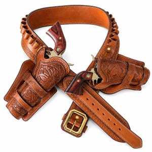 May include: A tan leather gun belt featuring two holsters with intricate floral tooling and stitching. The belt includes multiple cartridge loops and a brass buckle. Two revolvers with dark wood grips are secured within the holsters.