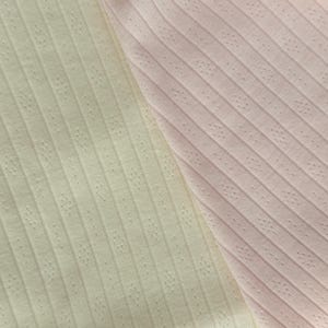 May include: A close-up shot of two fabric samples. One is a pale yellow, the other a light pink. Both have a ribbed texture with small, evenly spaced perforations, creating a dotted pattern. The diagonal lines of the ribs are visible.