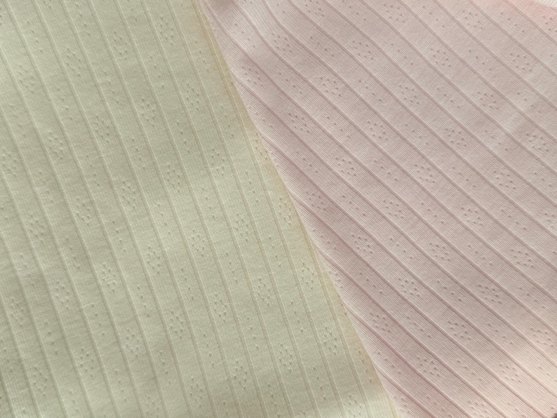 May include: A close-up shot of two fabric samples. One is a pale yellow, the other a light pink. Both have a ribbed texture with small, evenly spaced perforations, creating a dotted pattern. The diagonal lines of the ribs are visible.