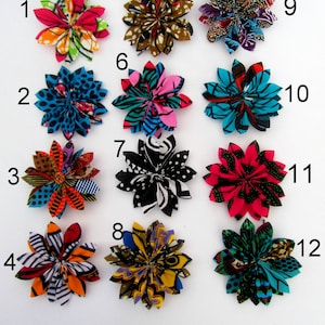 May include: Twelve fabric flower hair clips in various colors and patterns. The flowers are made from colorful African wax print fabric. The clips are numbered 1 through 12.