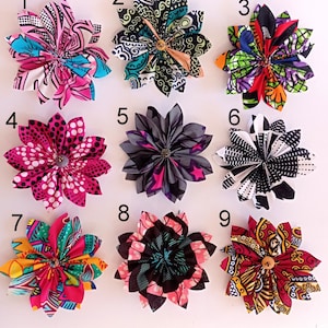 May include: Nine colorful fabric flower brooches with different patterns. The brooches are numbered 1 through 9.
