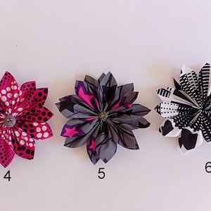 May include: Three fabric flowers with different patterns. The first flower is pink with white polka dots, the second flower is gray with pink stars, and the third flower is black and white with geometric shapes. The flowers are numbered 4, 5, and 6.