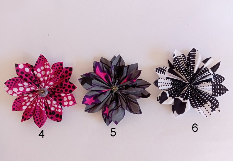 May include: Three fabric flowers with different patterns. The first flower is pink with white polka dots, the second flower is gray with pink stars, and the third flower is black and white with geometric shapes. The flowers are numbered 4, 5, and 6.