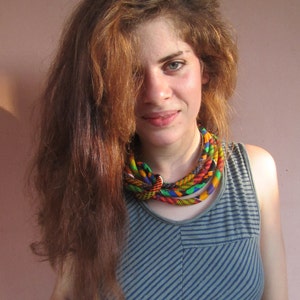 May include: A woman with long brown hair wearing a blue and white striped tank top with a colourful woven necklace.