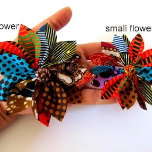 May include: Two fabric flowers, one large and one small, with a variety of colorful patterns and a brown button center. The flowers are made from African wax print fabric.
