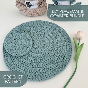 May include: A crocheted placemat and coaster set in a soft teal color. The placemat is round, and the coaster is a smaller, matching circle. The text "LILY PLACEMAT & COASTER BUNDLE" and "CROCHET PATTERN" are visible.