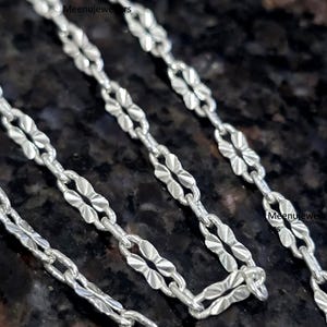 Op de afbeelding: Een witte keramische mok met een zwarte handgreep en de tekst "But First, Coffee" in een vetgedrukte, zwarte letter. De mok staat tegen een wazige achtergrond, wat een gezellige setting suggereert.