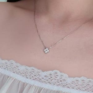 May include: A delicate silver necklace featuring a four-leaf clover pendant adorned with small, sparkling stones. The necklace is displayed against a soft, neutral background, highlighting the jewelry's intricate design and elegant simplicity.