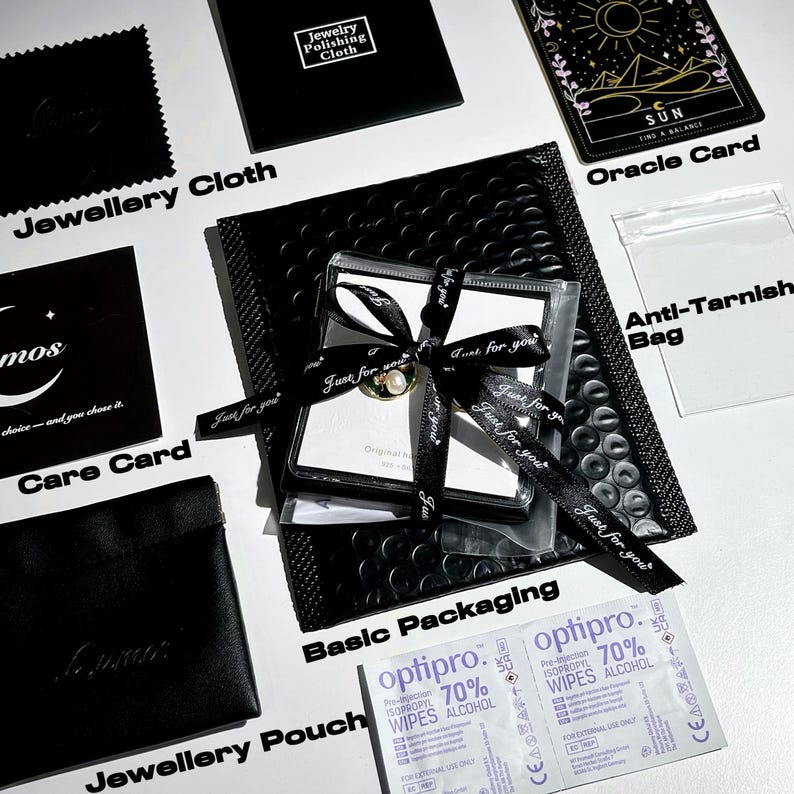 May include: An overhead shot of jewelry packaging, including a black pouch, care card, and polishing cloth. A ring is presented in a clear box tied with a black ribbon that reads "Just for you." An oracle card and alcohol wipes are also visible.