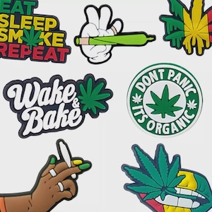 May include: A selection of cannabis-themed patches and stickers. The designs feature text such as "Eat Sleep Smoke Repeat" and "Wake & Bake", alongside illustrations of cannabis leaves and joints. The color scheme includes green, yellow, red, and white.