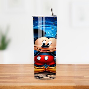 May include: A stainless steel tumbler featuring a vibrant illustration of Mickey Mouse. The design showcases Mickey against a blue night sky with stars. The tumbler includes a silver lid and a straw.