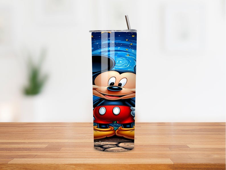 May include: A stainless steel tumbler featuring a vibrant illustration of Mickey Mouse. The design showcases Mickey against a blue night sky with stars. The tumbler includes a silver lid and a straw.