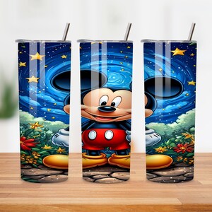 May include: A set of three stainless steel tumblers featuring a vibrant illustration of Mickey Mouse. The design showcases Mickey against a starry night sky with swirling blue and yellow accents. The tumblers have a straw and lid.