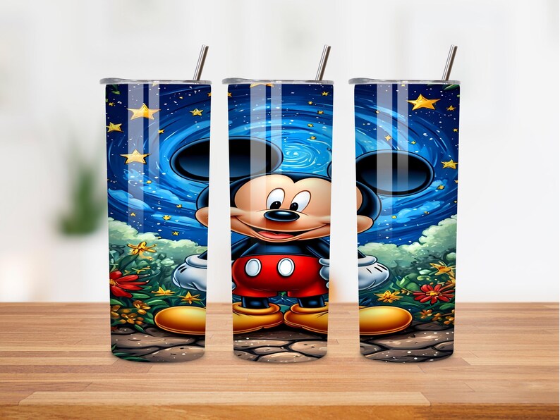 May include: A set of three stainless steel tumblers featuring a vibrant illustration of Mickey Mouse. The design showcases Mickey against a starry night sky with swirling blue and yellow accents. The tumblers have a straw and lid.