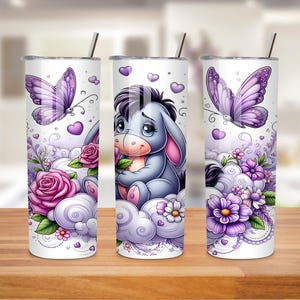 May include: Three white stainless steel tumblers with illustrations of a cartoon donkey, butterflies, flowers, and clouds. The tumblers have silver straws and lids. The design features purple, pink, and white colours.