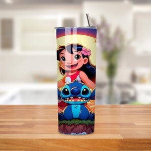 May include: A stainless steel tumbler featuring a colorful cartoon illustration of a girl and a blue alien-like creature. The design includes a pink flower and a sunset background. The tumbler has a silver lid and a straw.