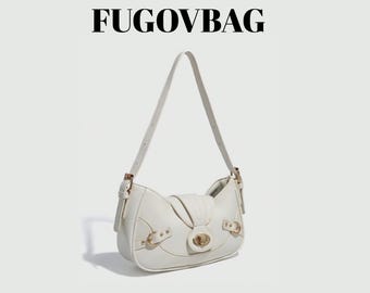 May include: A cream-coloured handbag with a curved design and a shoulder strap. It has gold-tone metal hardware, including buckles and a clasp. The brand name "FUGOVBAG" is displayed in bold, black letters at the top.