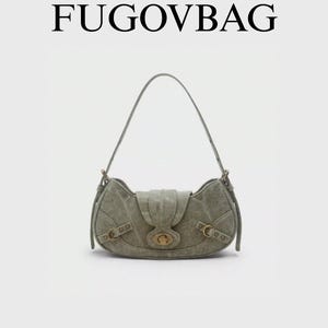 Peut inclure: Un sac à bandoulière vert sauge avec une forme incurvée et une fermeture à rabat. Le sac présente des détails de boucle et de sangle, avec le nom de la marque "FUGOVBAG" affiché en haut.