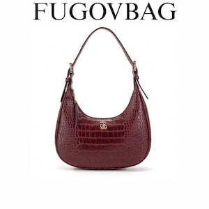 May include: A burgundy shoulder bag with a crocodile skin effect. The bag features a curved design, a single strap, and a gold zip. The brand name "FUGOVBAG" is displayed at the top.