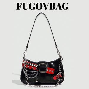 Puede incluir: Bolso de hombro negro con una correa de cadena plateada y elementos decorativos. El bolso presenta una correa roja y plateada con tachuelas, una hebilla plateada y un dije en forma de corazón. El texto "FUGOVBAG" está en la parte superior.