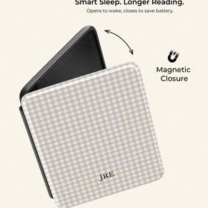 May include: A beige and white checked tablet case with the initials "JRE" on the front. The case has a magnetic closure and the text "Smart Sleep. Longer Reading." is displayed above the case.