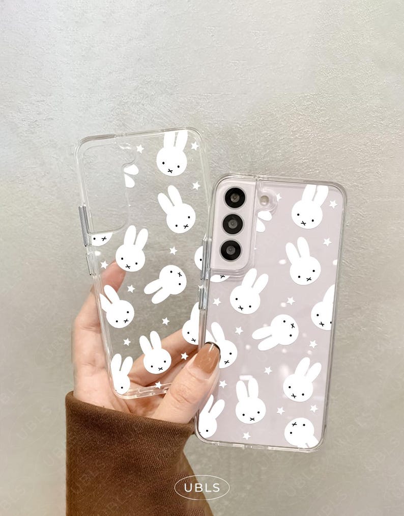 May include: Clear phone case with a white bunny and star pattern. The case is shown with a phone inside, and a separate empty case. The phone case has a camera cutout and button cutouts.