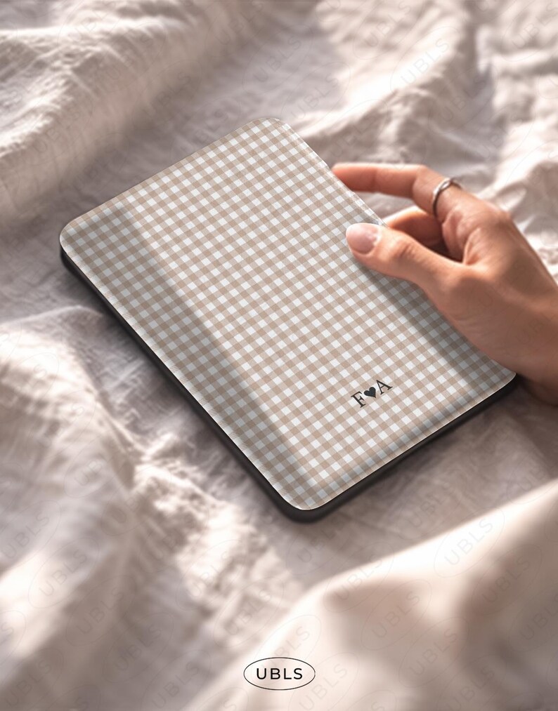 May include: A tablet case with a beige and white gingham design. The case has a black border and the initials "F♡A" in black. The case is on a white, textured surface.