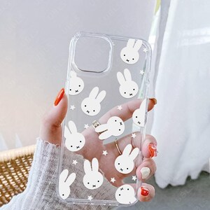 May include: Clear phone case featuring a repeating pattern of white bunny faces and stars. The case has a cutout for the camera and the brand name "UBLS" is printed at the bottom.
