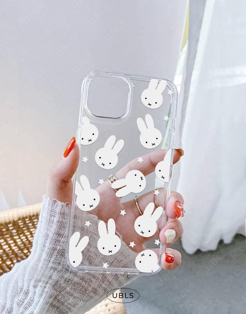 May include: Clear phone case featuring a repeating pattern of white bunny faces and stars. The case has a cutout for the camera and the brand name "UBLS" is printed at the bottom.