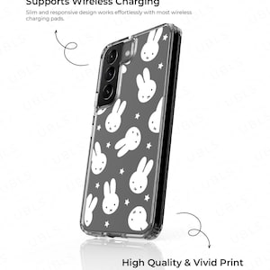 May include: Clear phone case with a gray background and white bunny and star pattern. The case has a black camera module and the text "Supports Wireless Charging" and "High Quality & Vivid Print".