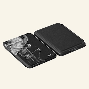 May include: Two black rectangular electronic reader cases. One case features a white graphic illustration of a skeleton with large wings and the letters S.L. The other case is solid black with a textured surface. The text UBLS appears at the bottom.