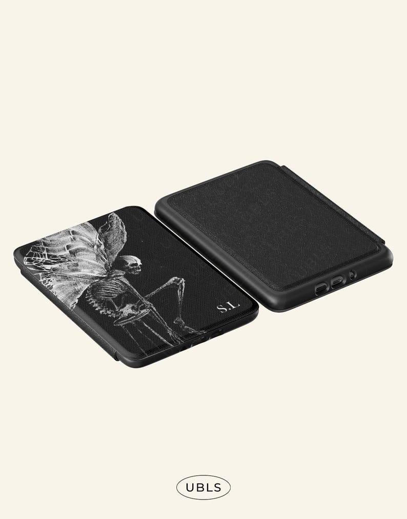 May include: Two black rectangular electronic reader cases. One case features a white graphic illustration of a skeleton with large wings and the letters S.L. The other case is solid black with a textured surface. The text UBLS appears at the bottom.