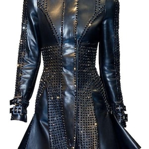 May include: Black leather coat with studded embellishments. The coat features a notched collar, long sleeves with buckle details, and a flared skirt. The design includes rows of studs and decorative stitching, creating a bold, edgy look.