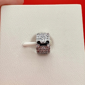 Puede incluir: Un charm plateado con un dise&ntilde;o de Mickey Mouse. El charm est&aacute; incrustado con cristales transparentes, con una silueta negra de Mickey Mouse en el centro. El charm est&aacute; sobre un fondo blanco.