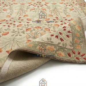 May include: Beige floral area rug with a detailed pattern of orange and red flowers and green leaves. The rug has a green border and the text "THE RUG HOMES".