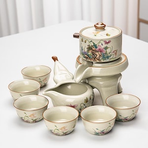 Può includere: Un set da tè completo con finitura color crema. Il set include una piccola teiera, una brocca da portata, un distributore d'acqua e sei piccole tazze. Ogni pezzo è decorato con disegni floreali e farfalle nei toni del rosa, verde e giallo.