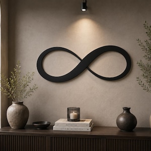 May include: A matte black infinity symbol wall art piece mounted on a neutral-toned wall. The design features a continuous, smooth loop shape that represents the mathematical symbol for infinity, centered horizontally above a wooden console table.
