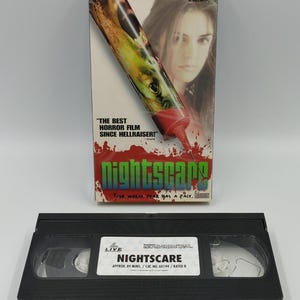 Może przedstawiać: Kaseta VHS Nightscare wraz z kartonowym opakowaniem. Na opakowaniu znajduje się grafika strzykawki, twarz kobiety oraz tekst: Craig Fairbrass, Elizabeth Hurley, Keith Allen, The best horror film since Hellraiser, Nightscare, Your worst fear has a face.