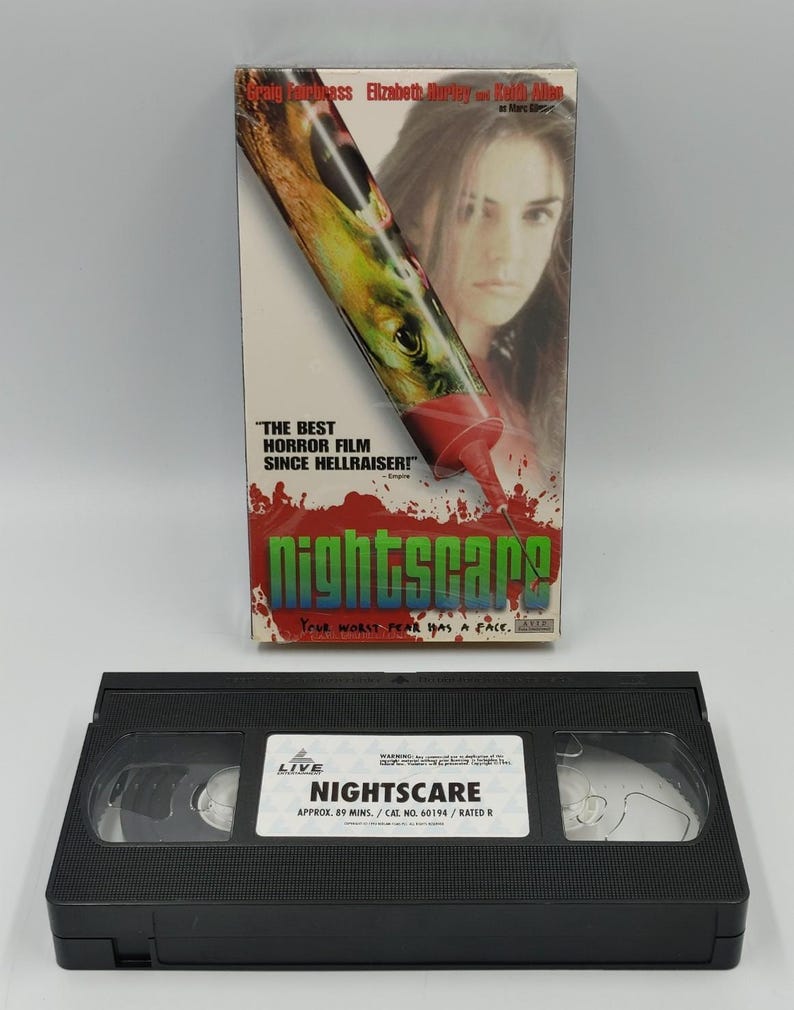 Może przedstawiać: Kaseta VHS Nightscare wraz z kartonowym opakowaniem. Na opakowaniu znajduje się grafika strzykawki, twarz kobiety oraz tekst: Craig Fairbrass, Elizabeth Hurley, Keith Allen, The best horror film since Hellraiser, Nightscare, Your worst fear has a face.