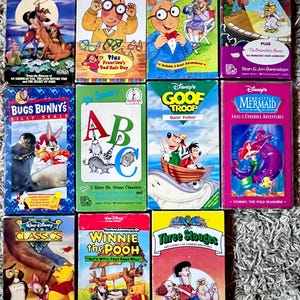 May include: A selection of vintage VHS tapes, including animated films and children's programmes. Titles include "All Dogs Go to Heaven," "Arthur's Eyes," "Bugs Bunny's Silly Seals," "Winnie the Pooh," and "The Little Mermaid." The tapes feature diverse colours and designs.