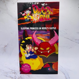 May include: A Dragon Ball VHS tape featuring cartoon characters and the title "Sleeping Princess in Devil's Castle." The box has a red and purple background with the words "New Release" and "Uncut Theatrical Movie."