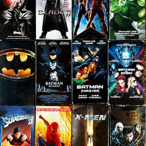 May include: A collection of twelve superhero movie VHS tapes featuring Blade, Blade II, Daredevil, Hulk, Batman, Batman Returns, Batman Forever, Batman and Robin, Superman II, Spider-Man, X-Men, and X2: X-Men United with their respective cover art.